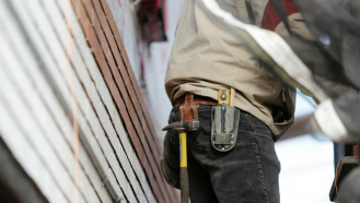 Mann mit Hammer auf Gerüst